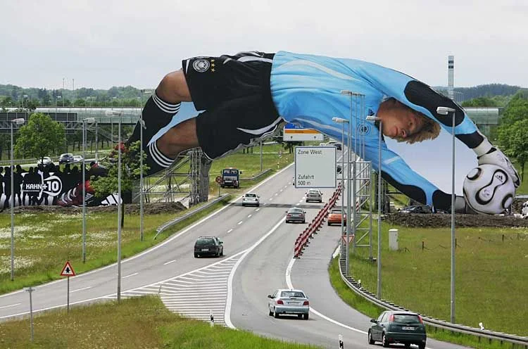 Iklan luar ruang adidas berupa figur raksasa kiper Oliver Kahn yang melintang di atas jalan dekat Bandara Munich, Mei 2006