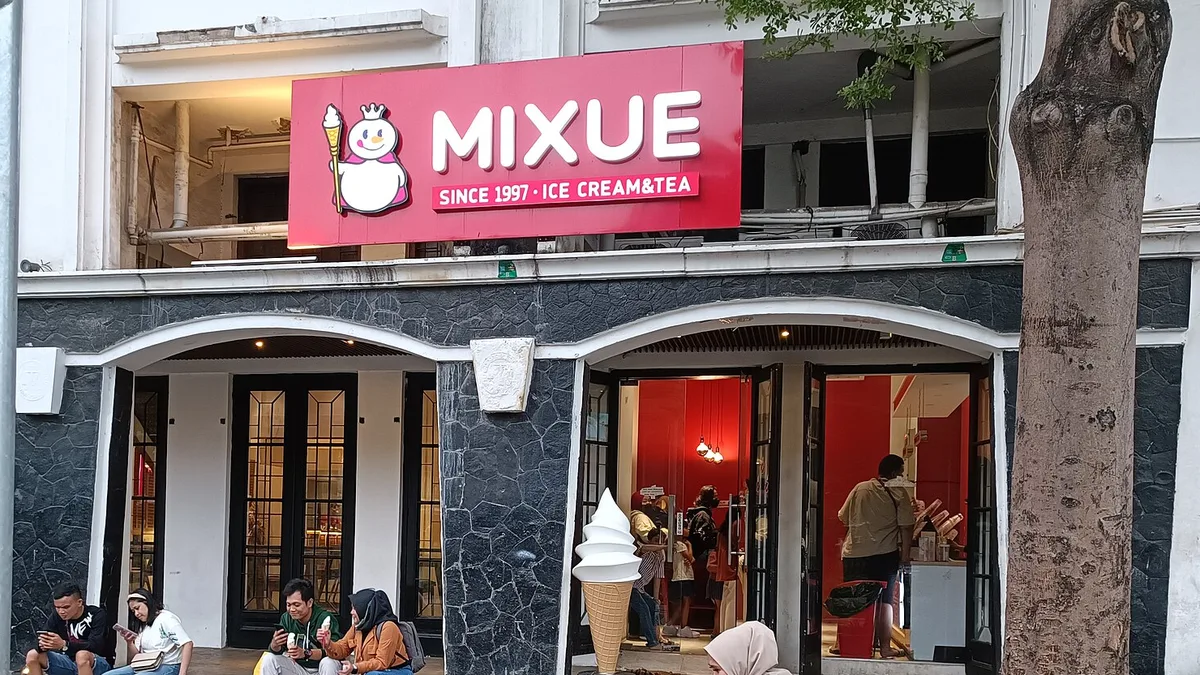 Papan nama merah gerai Mixue di kawasan Kota Tua Jakarta dengan maskot Snow King, manusia salju bermahkota yang memegang tongkat es krim, di samping tulisan MIXUE Since 1997 Ice Cream and Tea